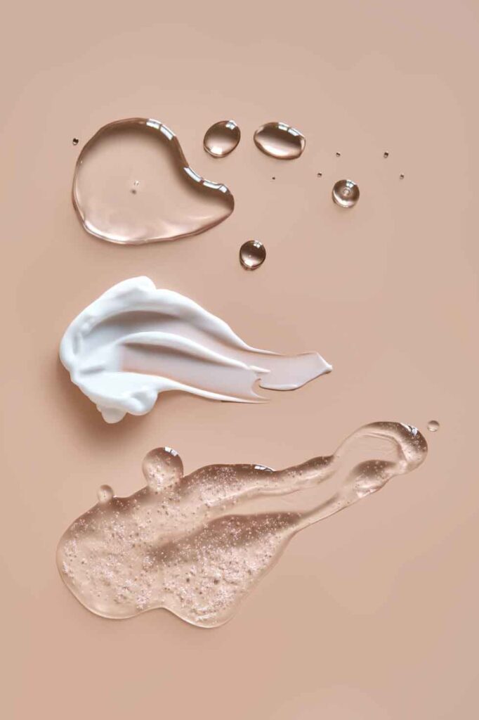 Forskellige hudplejeprodukter spredt ud på en ensfarvet baggrund, herunder olie, creme og gelé